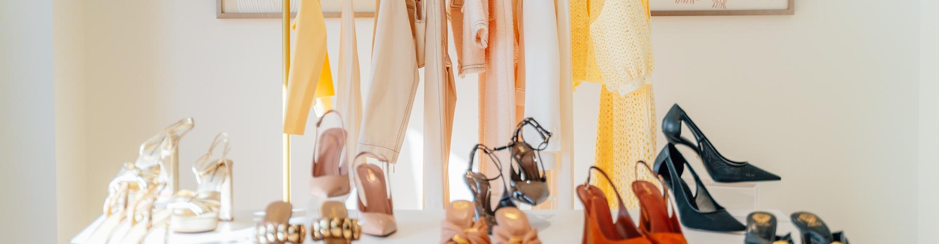 Rack of pastel spring clothing above a display of heeled sandals