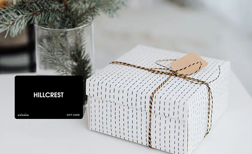 Black Hillcrest Plus gift card beside a white gift box tied with string