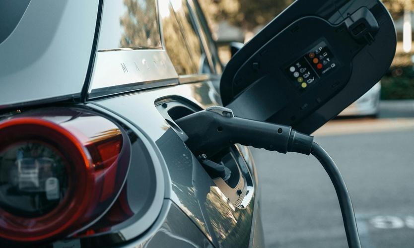 Charging cable plugged into a grey electric car's charging port