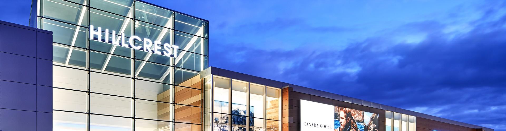 Lit Hillcrest mall exterior at dusk with a Canada Goose ad panel