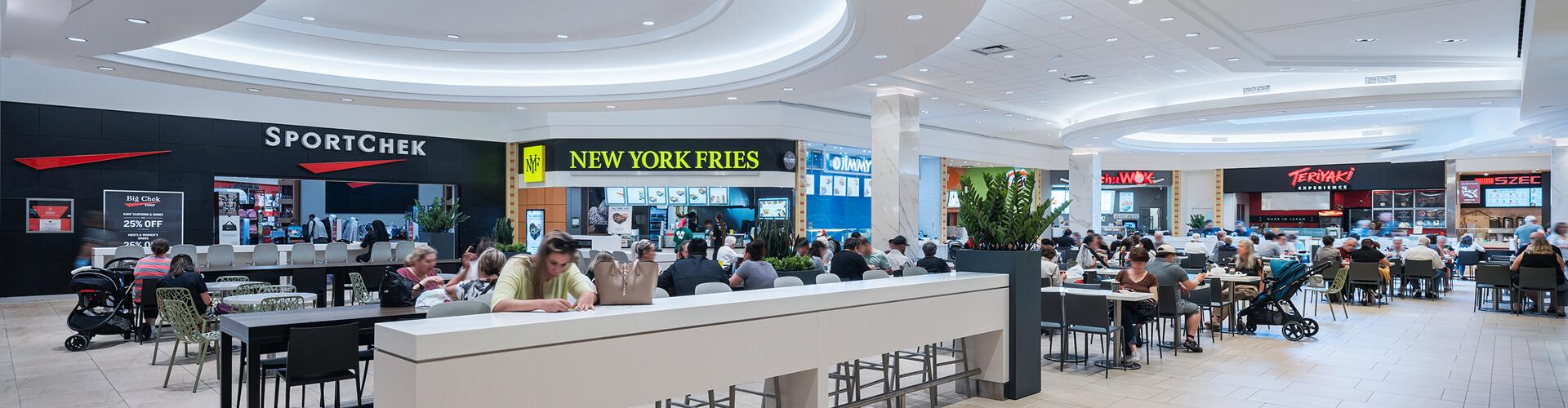 Busy mall food court with SportChek and New York Fries under a domed ceiling