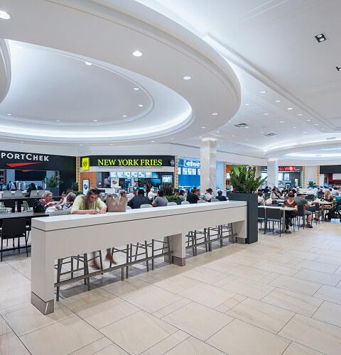 Busy mall food court with SportChek and New York Fries under a domed ceiling