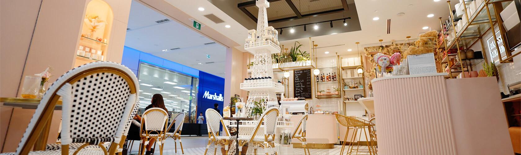 Parisian-style mall cafe with bistro chairs and a white Eiffel Tower display
