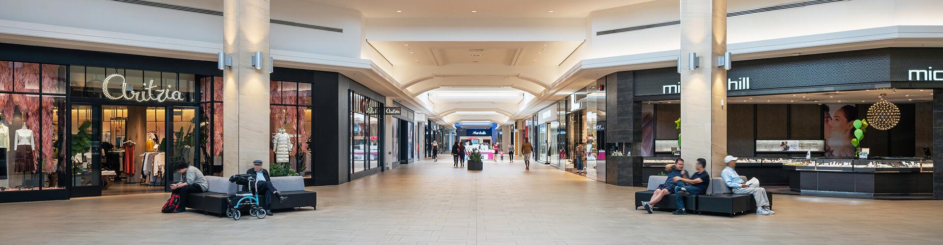 Wide mall concourse with Aritzia and Michael Hill stores and seating