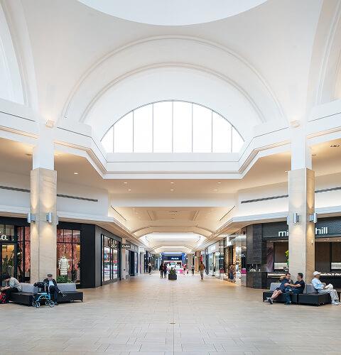Wide mall concourse with Aritzia and Michael Hill stores and seating