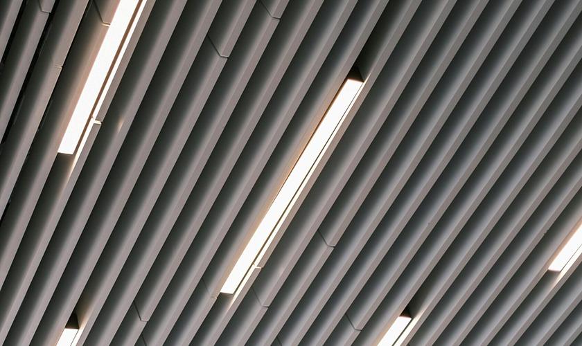 Angular white slatted ceiling with recessed linear lighting