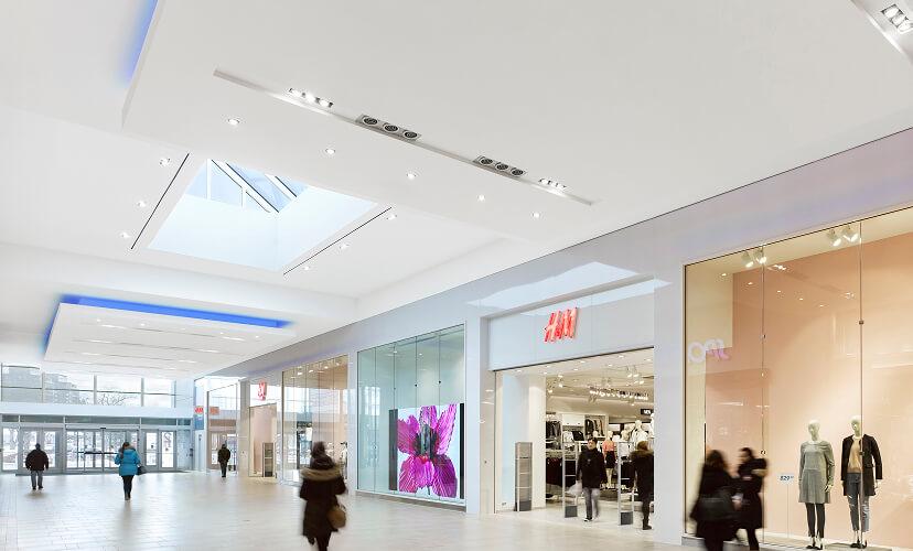 Bright mall interior with skylight and H&M storefront and shoppers