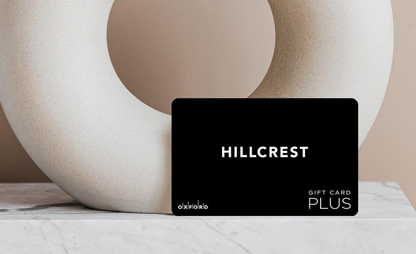 Black Hillcrest Plus gift card leaning against a white sculpture on marble