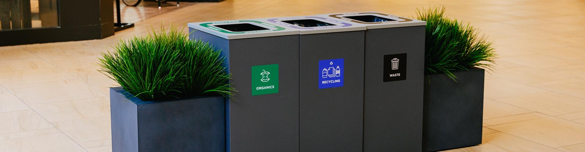 Organics, recycling and waste sorting bins between planters in a mall
