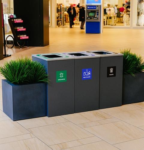 Organics, recycling and waste sorting bins between planters in a mall