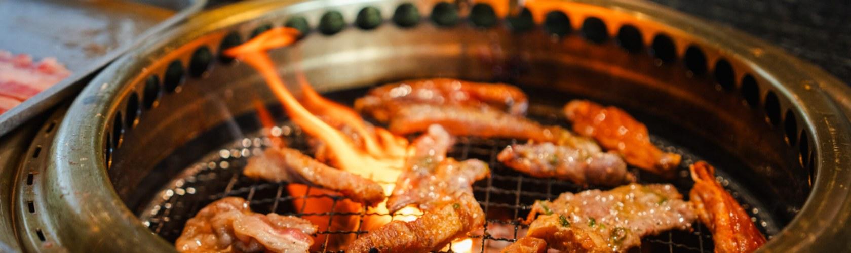 Marinated beef strips grilling over flames on a Korean BBQ tabletop grill