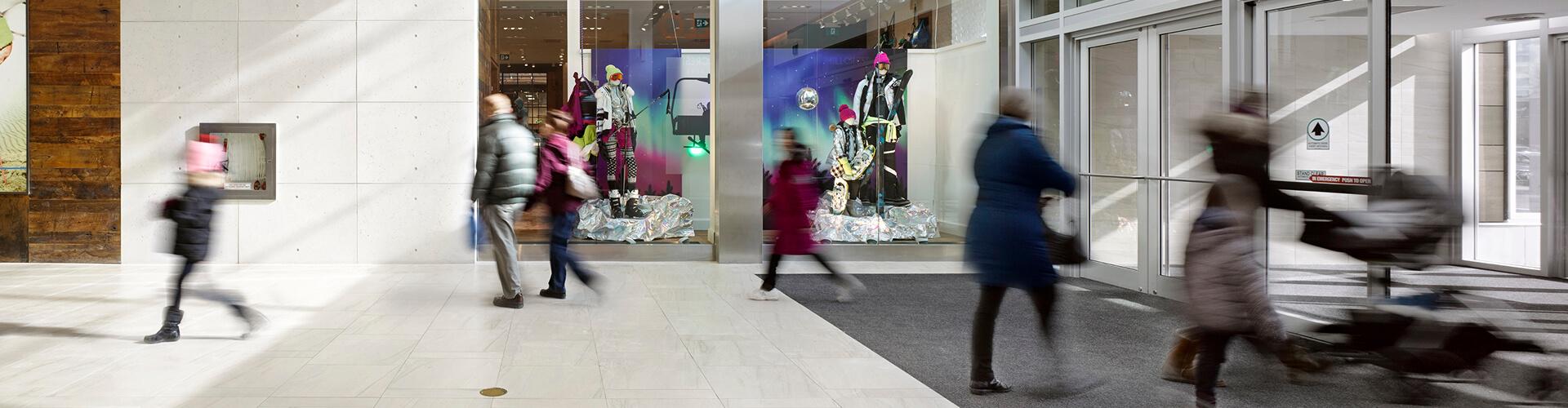 Blurred shoppers hurrying past a winter store window display in a mall