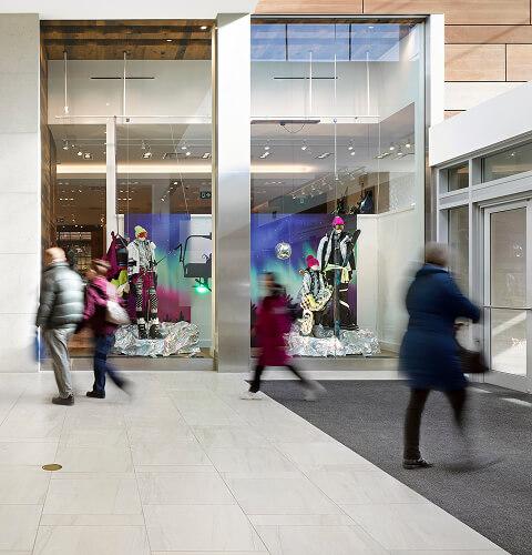 Blurred shoppers hurrying past a winter store window display in a mall