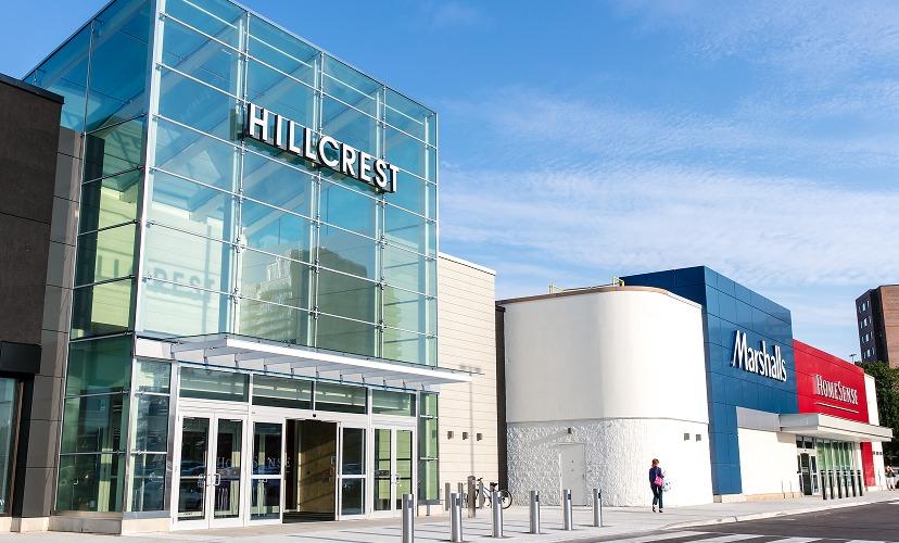 Glass Hillcrest mall entrance beside Marshalls and HomeSense under blue sky