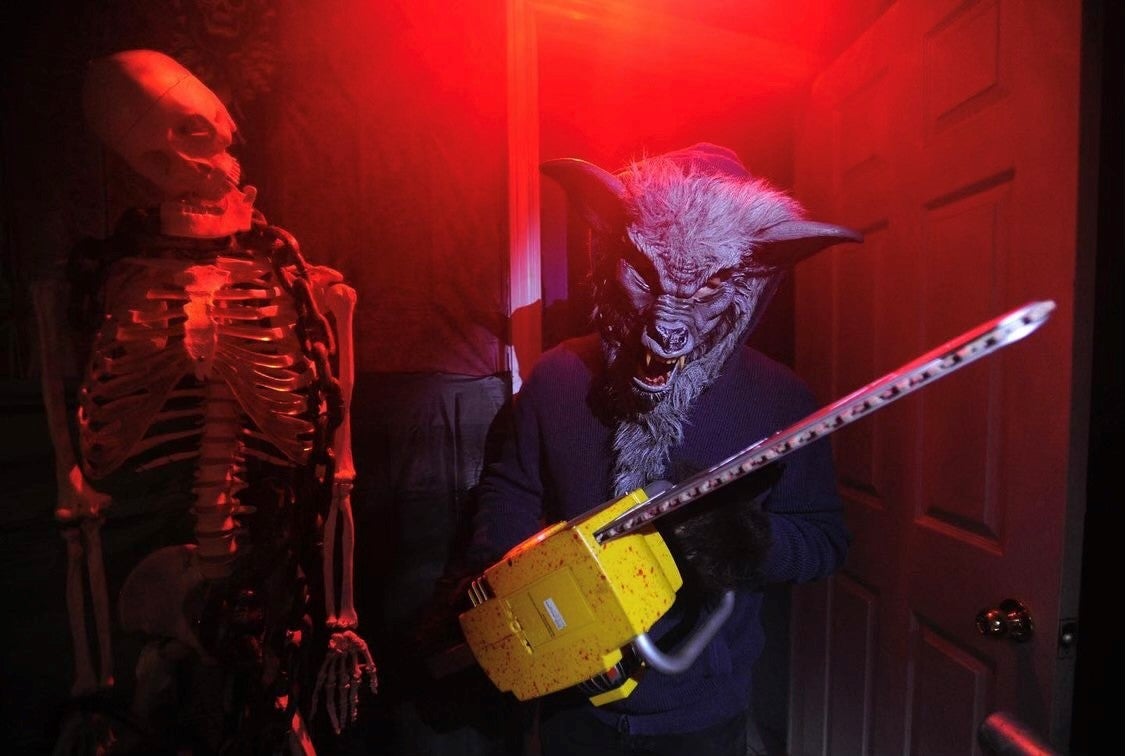 person wearing scary mask holding chainsaw