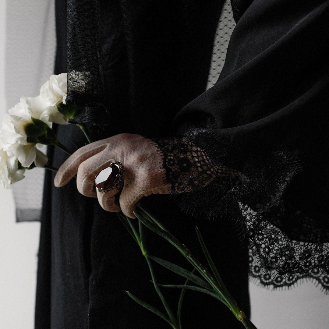 Woman wearing a black lace dress with a black ring