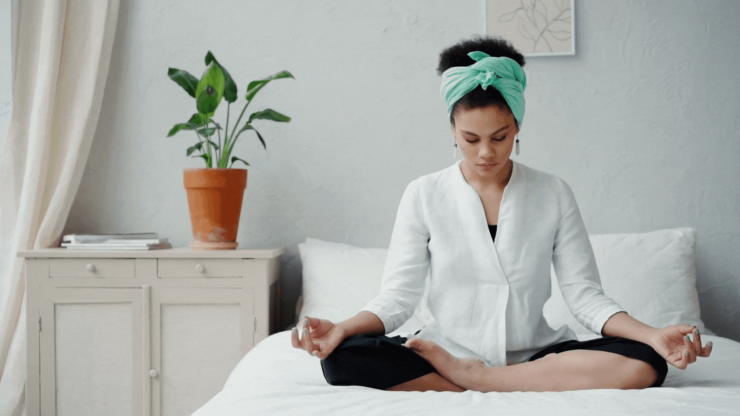 Woman meditating on her bed