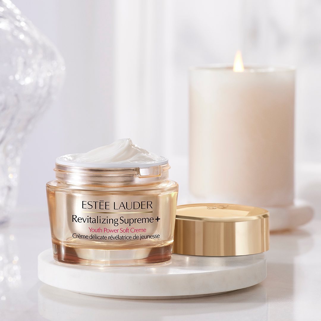 Estee Lauder face cream is showcased alongside a white candle on a white background.