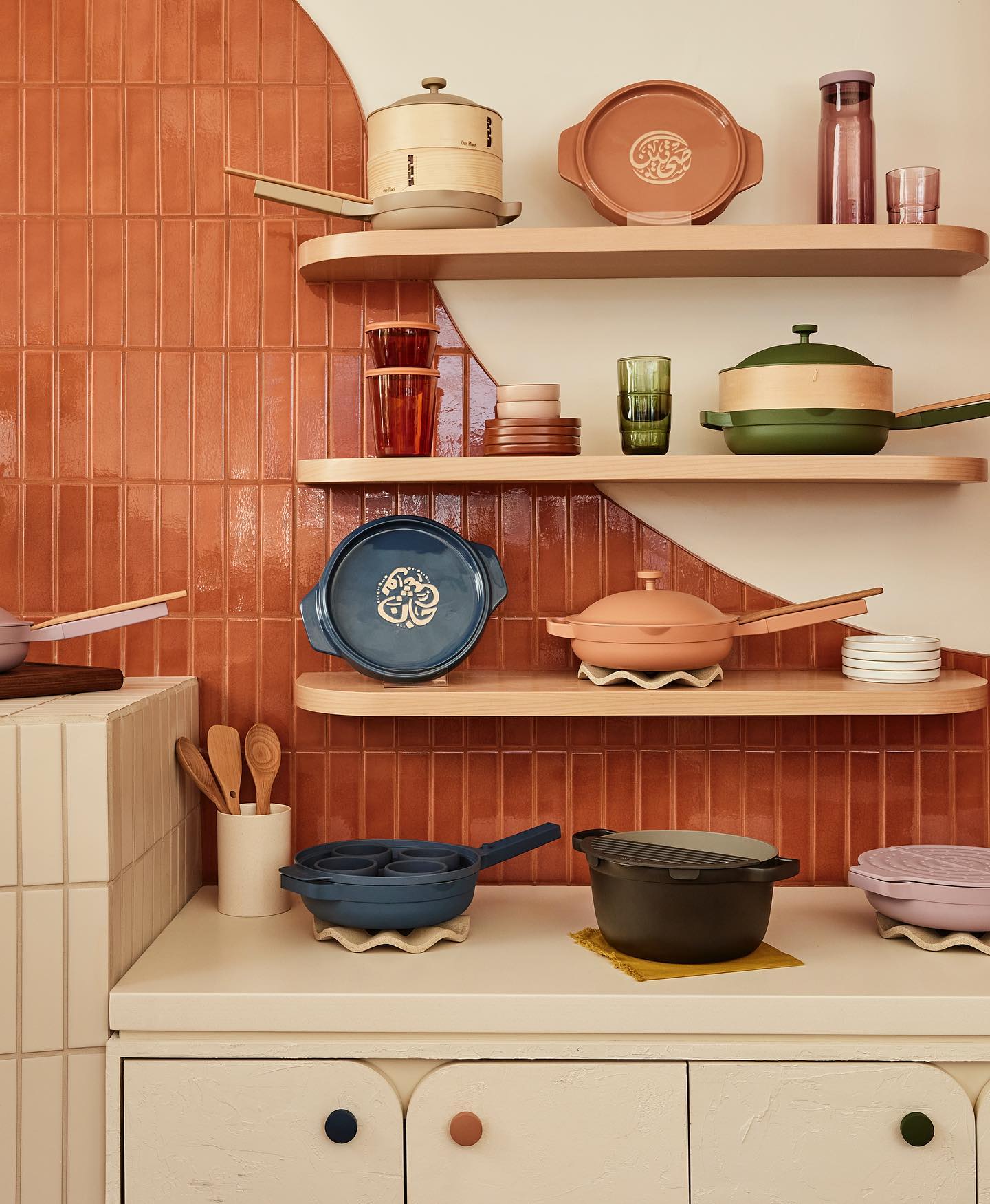 Various pots and pans from Our Place are on display in a retro inspired kitchen wall.