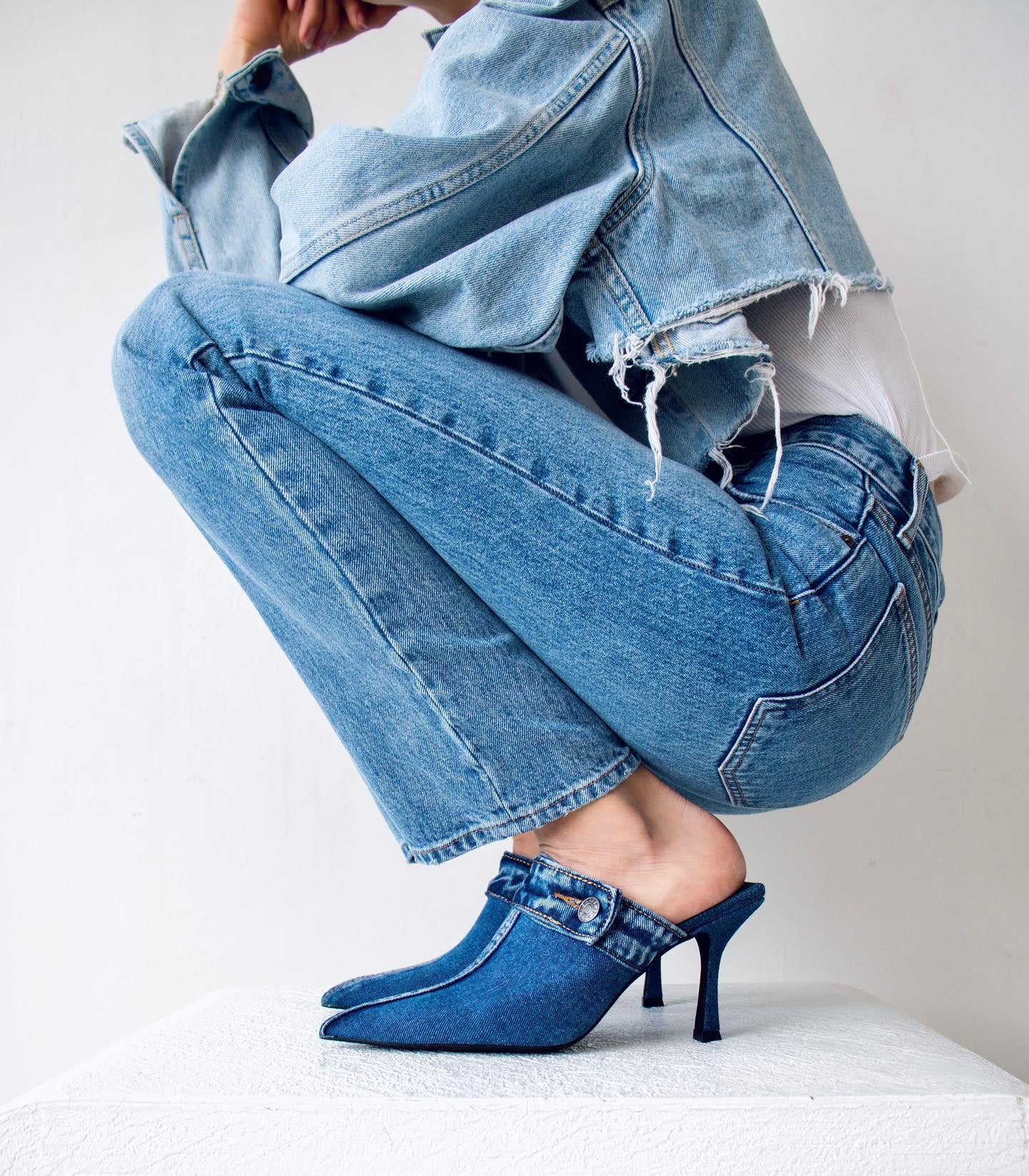 woman wearing denim heeled mules, jeans and a jean jacket