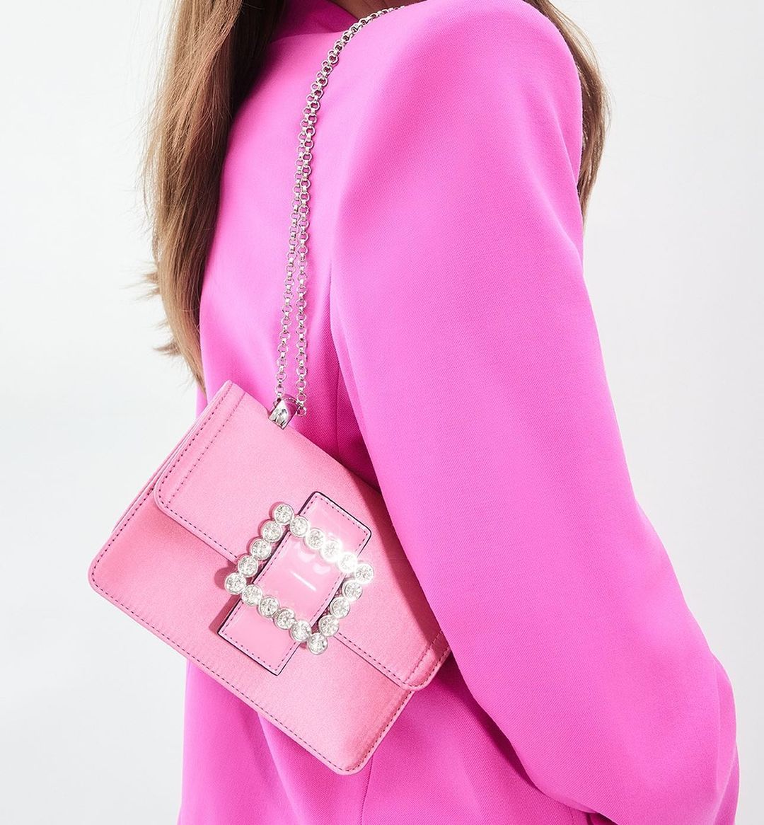 close-up image of a model in a pink blazer wearing a pink Aldo handbag with crystal embellishments on the buckle