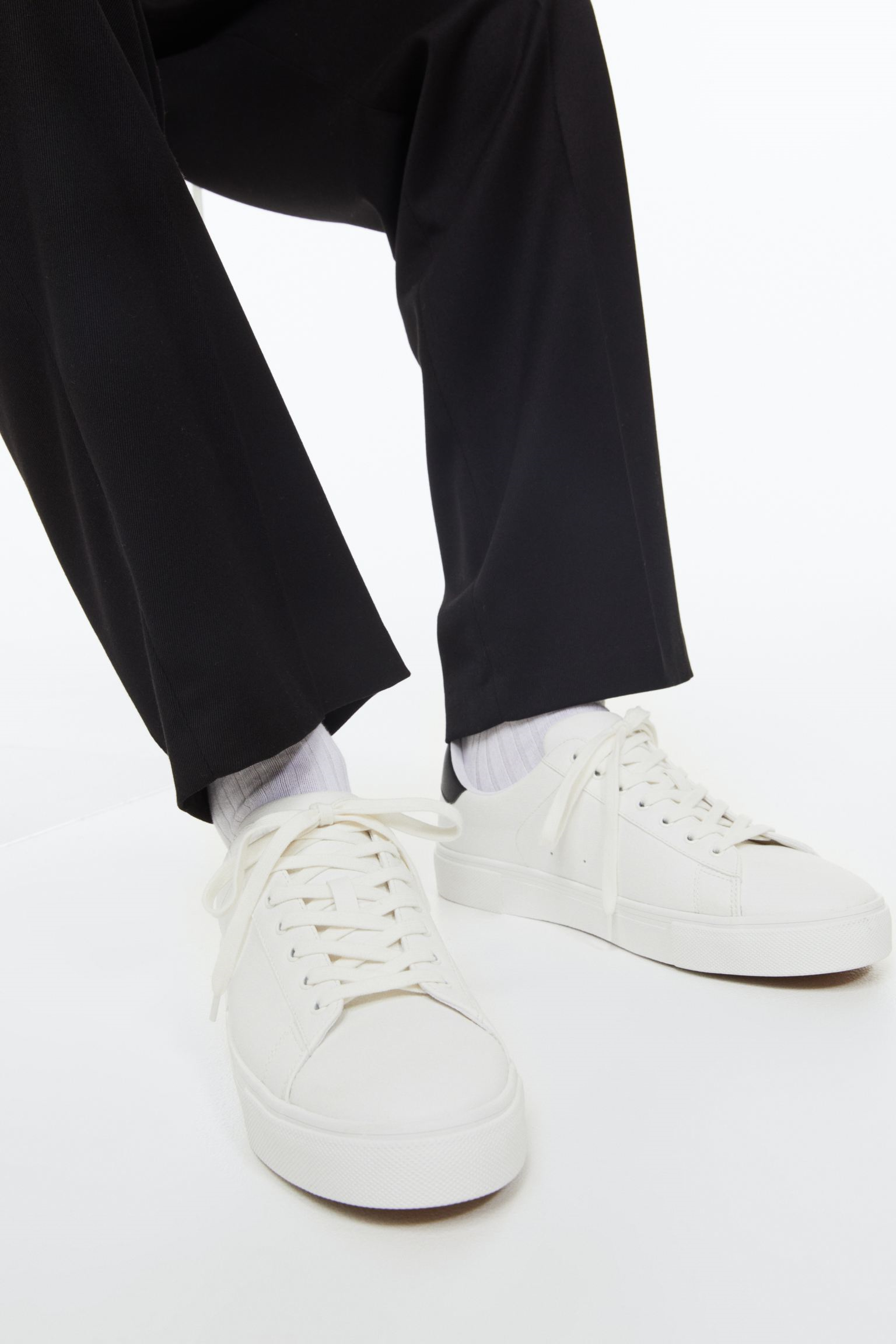close-up image of a model wearing black pants and white sneakers