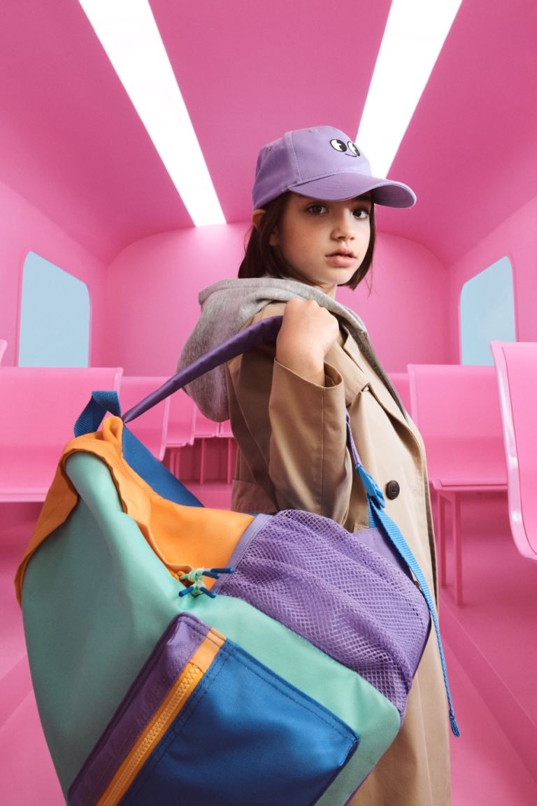 image of a young girl in a pink room holding a multicoloured backpack