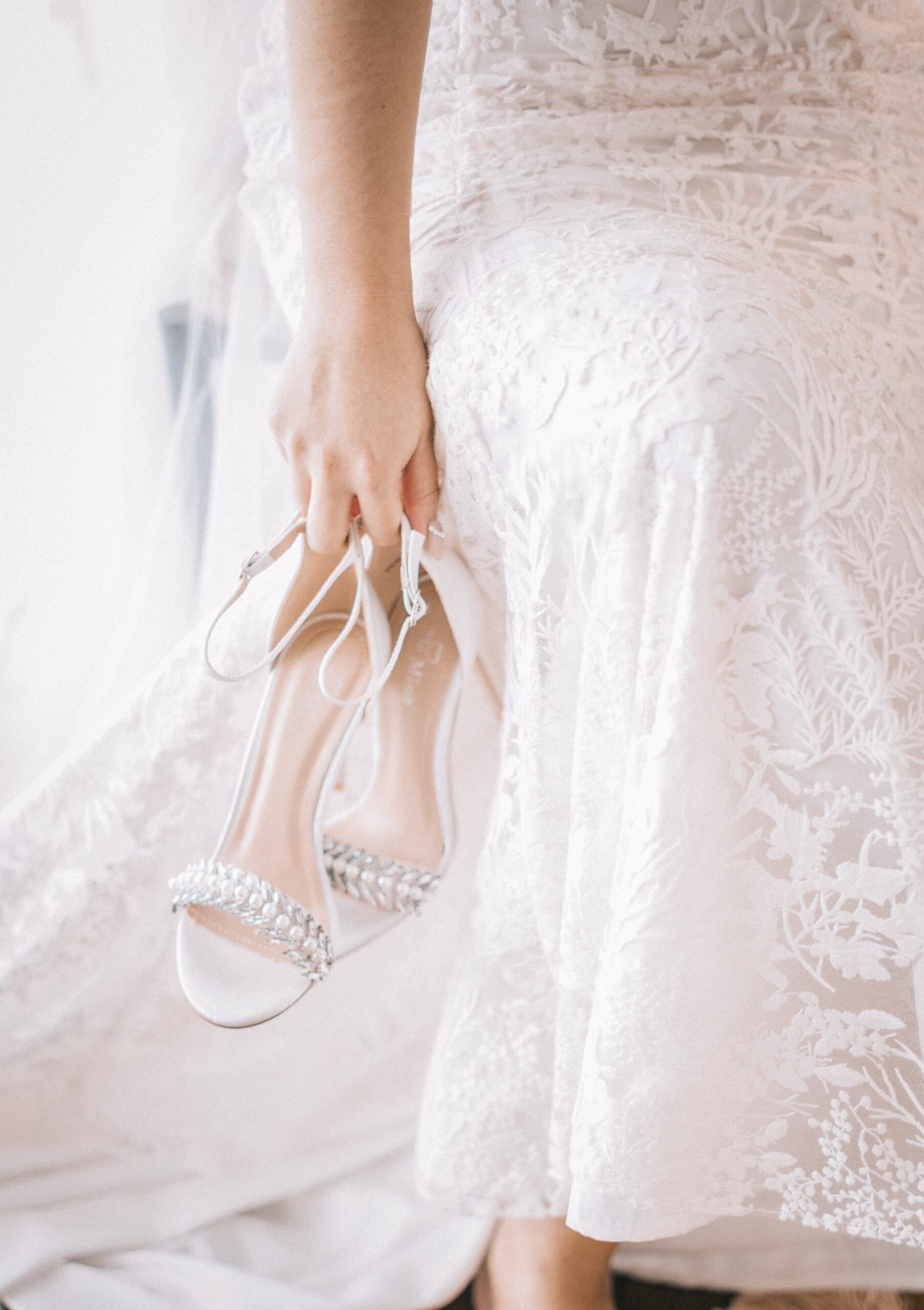 Hand holding heels with a wedding dress