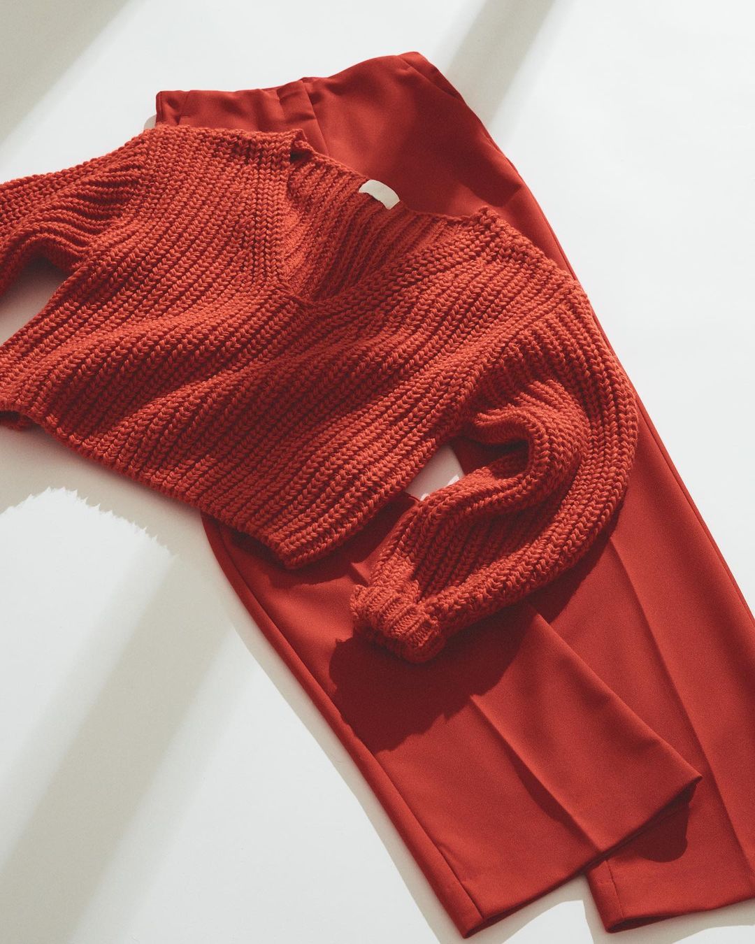 Red trousers with a red knit sweater laid over top.
