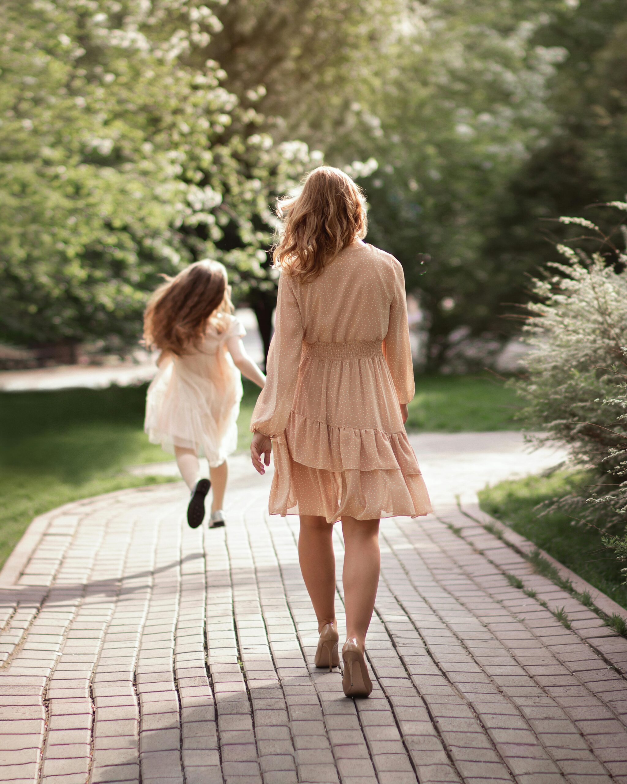 Woman and girl walking on paved path