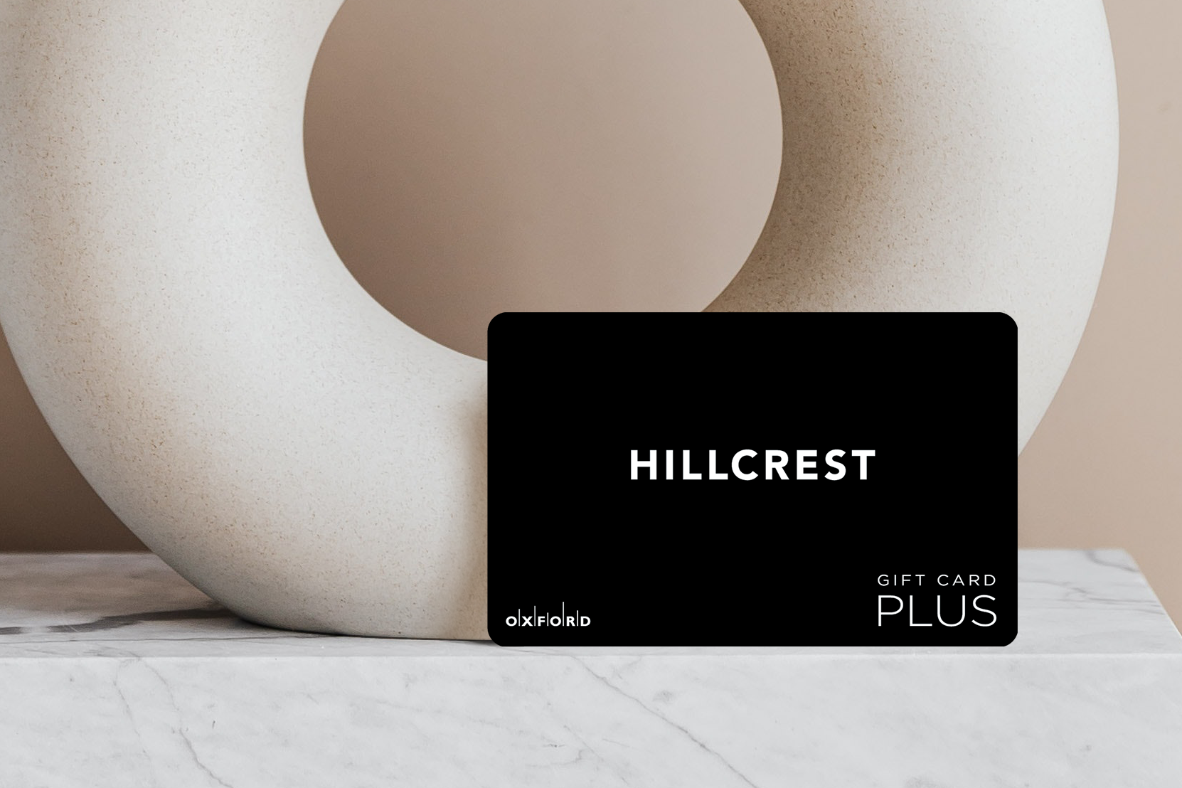 a promotional image of a black Hillcrest gift card in front of a neutral ceramic circular vase