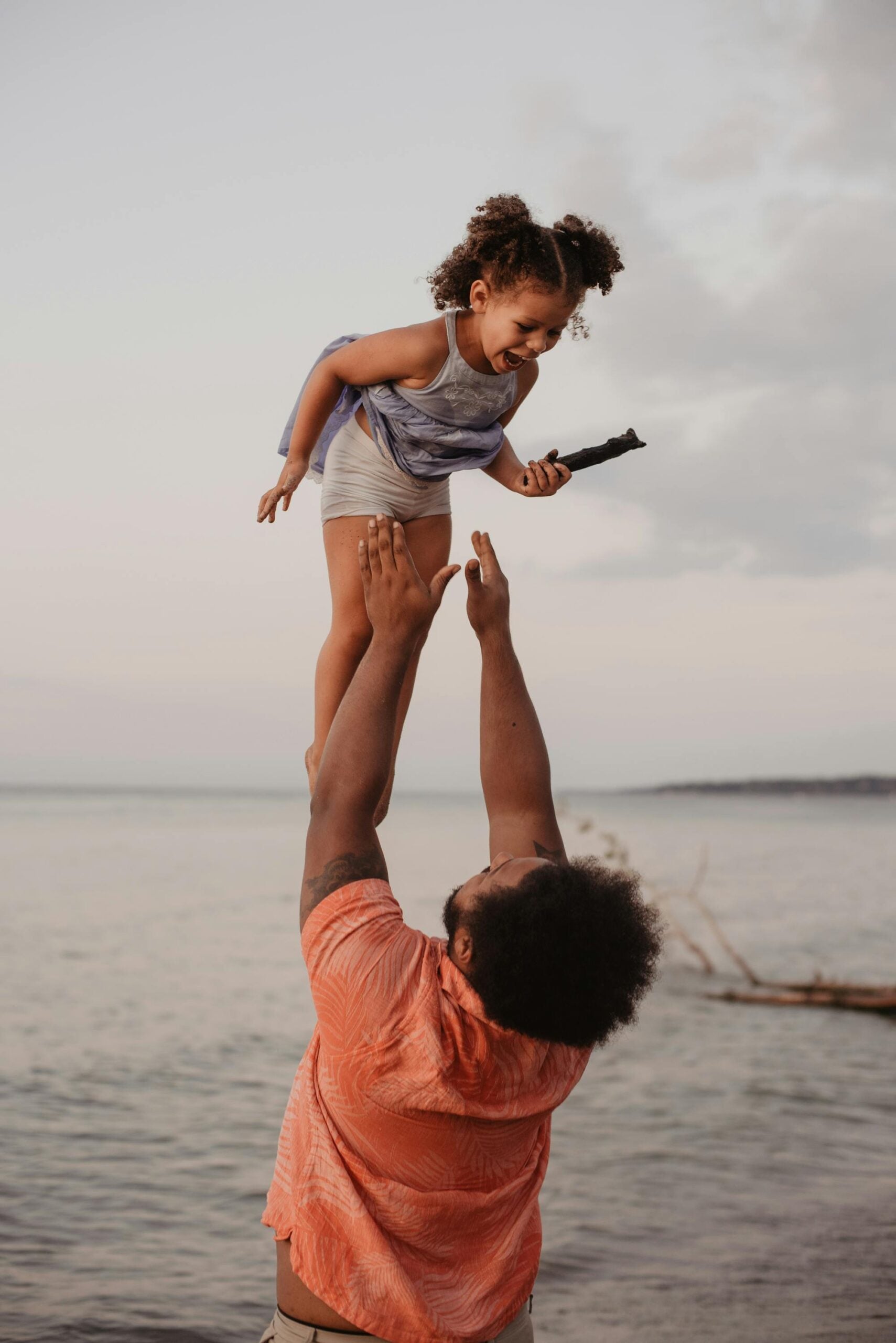 Father throwing his daughter up in the air at the beach