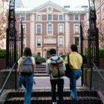 three students walking up steps to go to school