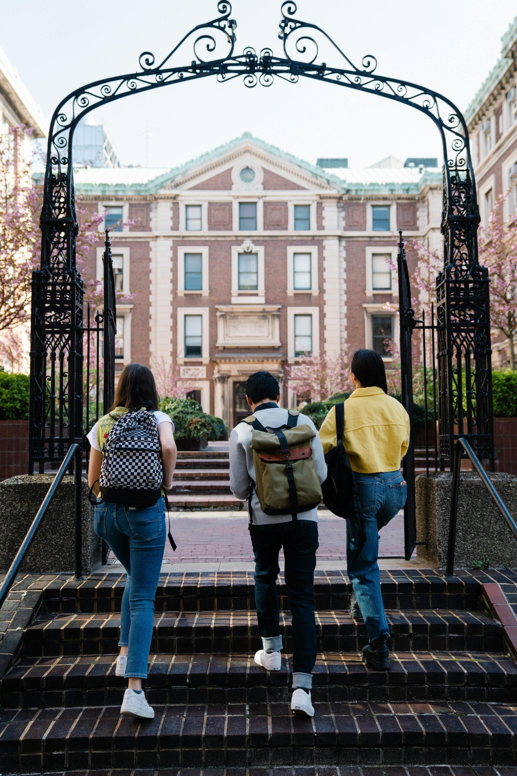 three students walking up steps to go to school